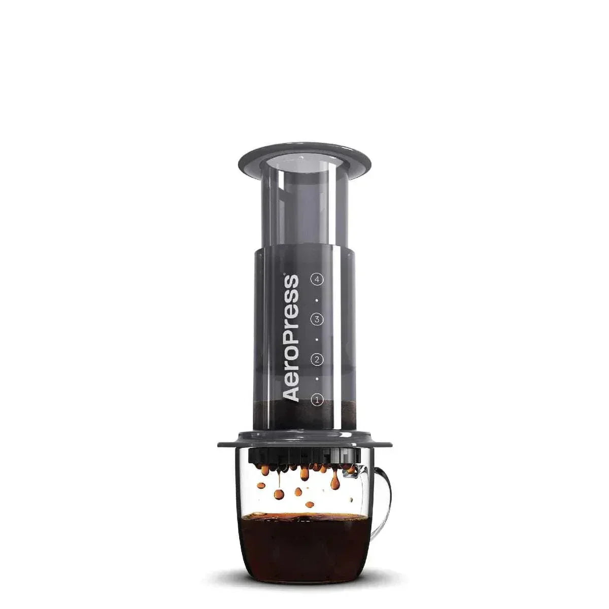 Aeropress coffee maker brewing espresso over glass mug with coffee drops
